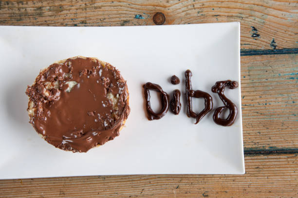 Dibs written with chocolate fudge nutella spread on bun donut Dibs written with chocolate fudge nutella spread on bun donut dibs stock pictures, royalty-free photos & images