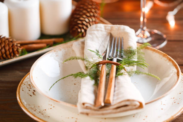 istock Decorated Thanksgiving or New Year table setting among white candles and winter decor. The concept of a festive dinner. 1053016798