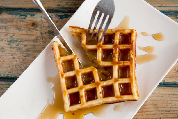 istock Waffle with maple syrup cutting in half with knife and a fork 1053017108