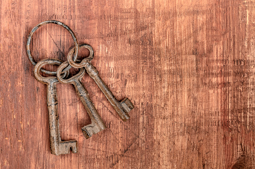 An overhead photo of old keys on a ring, on a dark rustic texture with copy space