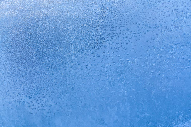 istock Blue frozen window glass with icy drawing with fine structure as backgroundr. 1053023190