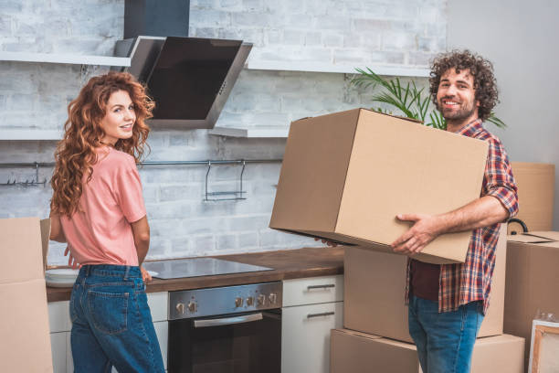 istock smiling couple unpacking cardboard boxes together at new kitchen and looking at camera 1053024992