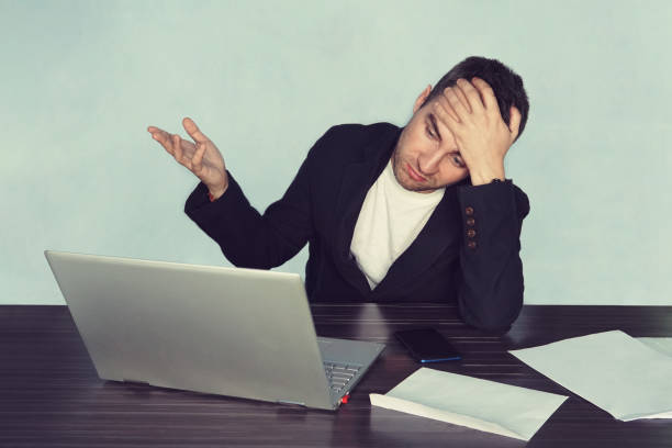 istock The young surprised man with his laptop computer, disappointment in business. problem at work. Crisis in business processes. unhappy face. loss of profit and money 1053025122