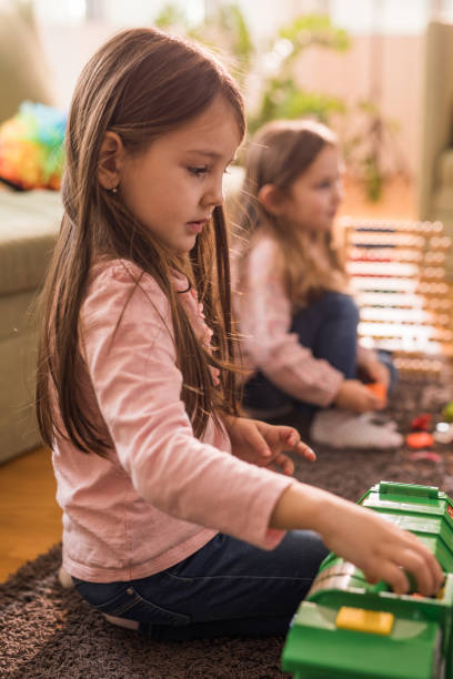 istock Small girls having fun while playing with toys at home. 1053029002