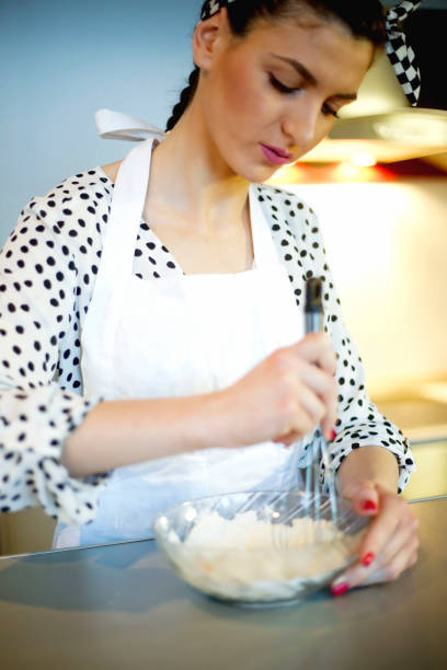 istock Young woman making dough at table in kitchen 1053030992
