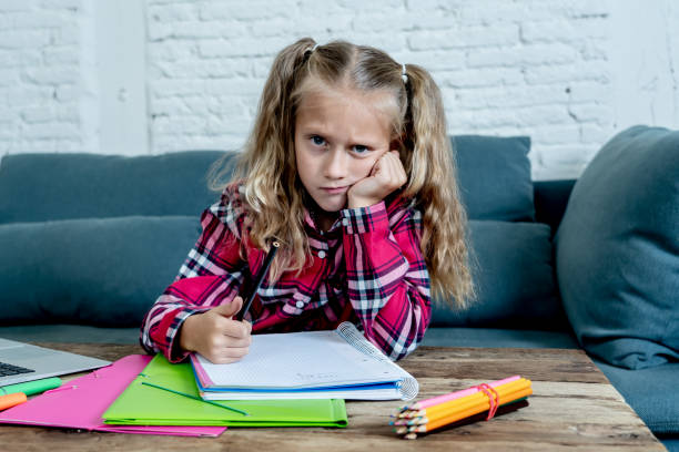 istock Beautiful cute blonde 9 years elementary student feeling sad bored and a overwhelmed trying to study at home in learning difficulties exams homework and school education concept. 1053031012