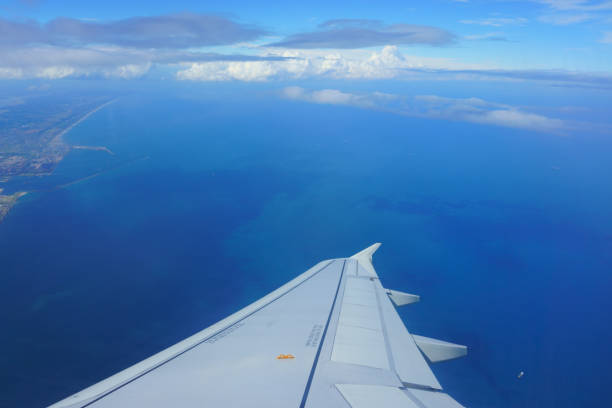 istock wing of plane view from airplane. blue sky, sea, coast 1053043140