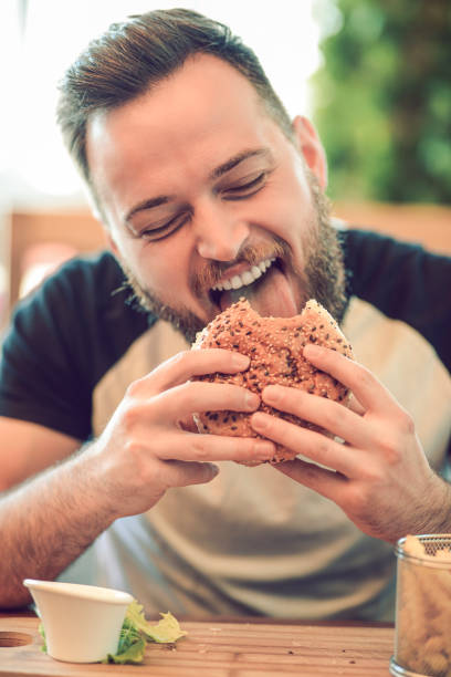 istock Handsome Male Eating Burger In Restaurant 1053044282