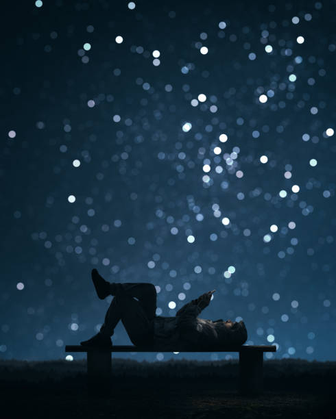 istock A man is lying on a bench and using a smartphone. Starry sky bokeh In the background 1053048948