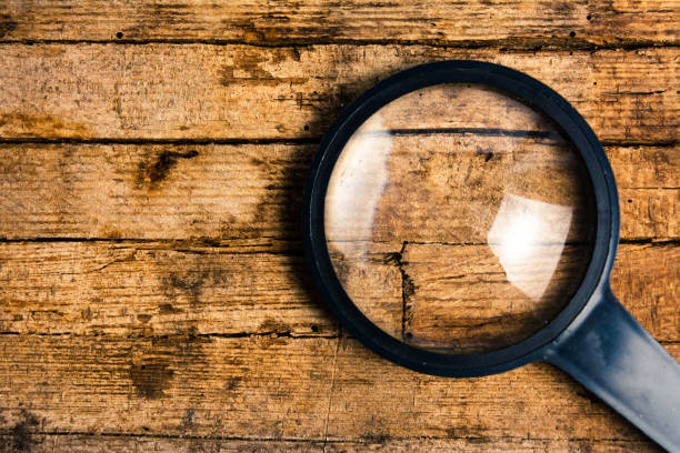 istock Magnifying glass on rustic wooden background 1053057528