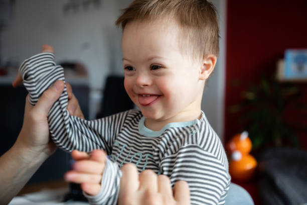 Cute boy with Down syndrome playing with dad on in home Cute boy with Down syndrome playing with dad on in home living room down syndrome photos stock pictures, royalty-free photos & images