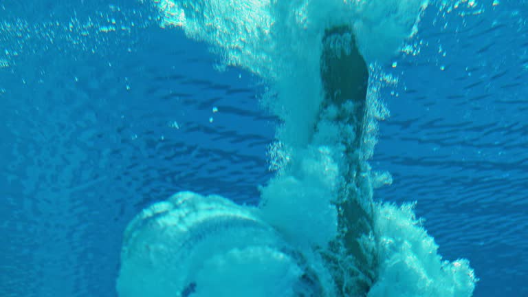 SLO MO LD High diver doing an underwater flip when hitting the pool