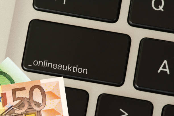 istock Euro banknotes and computers with the button online auction 1053073674