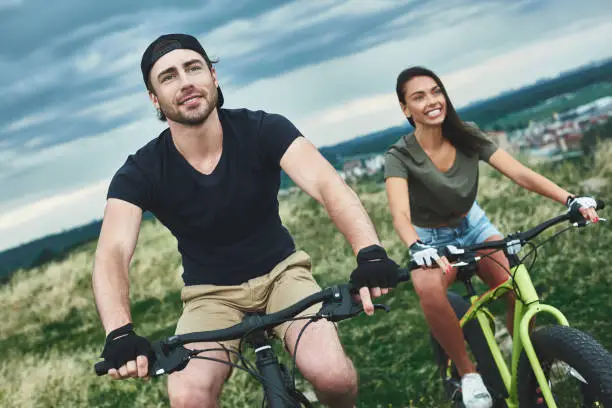 Couple riding bicycles one after another. Cropped photo, front view