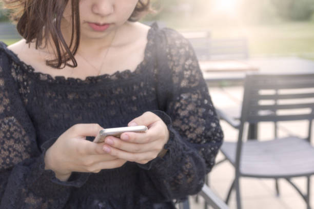 Japanese teenage girl using smartphone at a cafe.