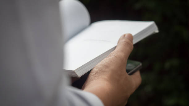 istock Man reading Book in his hands at garden 1053078216