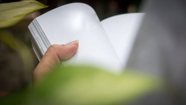 istock Man reading Book in his hands at garden 1053078234