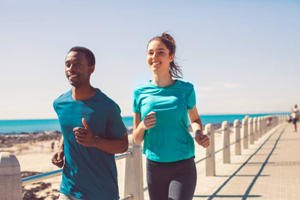 istock Smiling young couple jogging on promenade at beach 1053081196