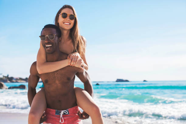 istock Cheerful young man giving piggyback to girlfriend 1053081418