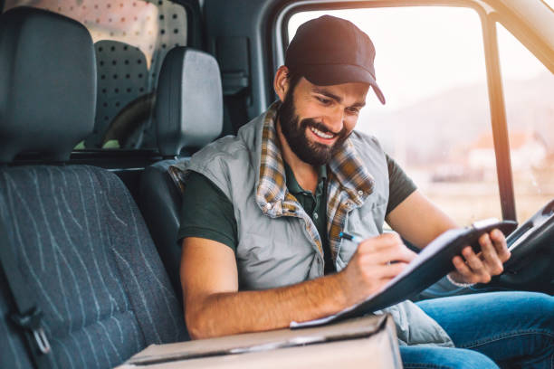 updating his delivery status - postal worker truck driver delivering delivery person imagens e fotografias de stock