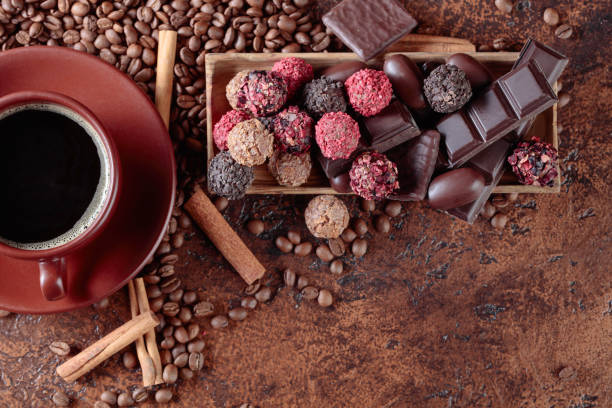 vari cioccolatini e tazza di caffè nero. - brown chocolate candy bar close up foto e immagini stock