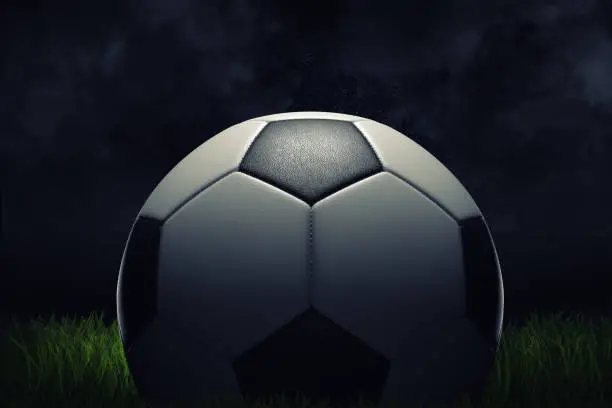 3d rendering of a single football ball standing on a grass field on a dark background. Football field. Scoring goal. Sport under projectors.