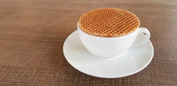 Photo of Stroopwafel a famous waffle from dutch on the black coffee cup