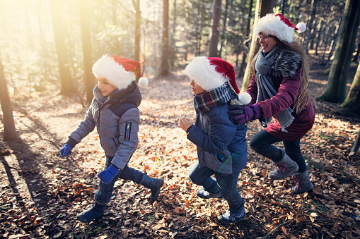 Kids enjoying running in snowless forest on Christmas