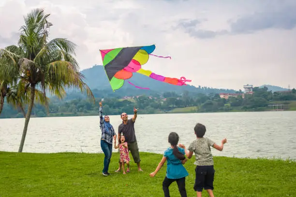 Photo of A muslim family is playing kite at the park.