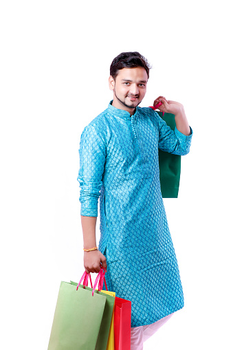 Indian man in ethnic wear with shopping bags, isolated over white background