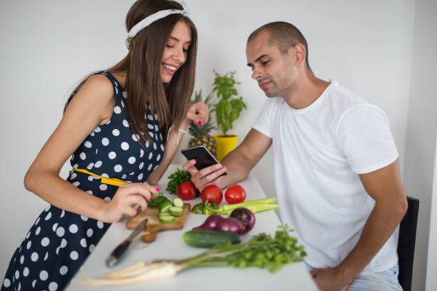 istock Young couple in the kitchen looking smartphone 1053107268