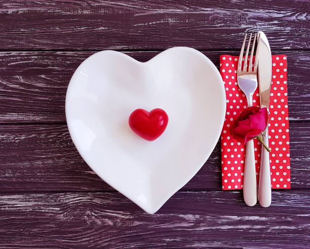 istock fork, knife, plate heart, flower rose on wooden background 1053109538