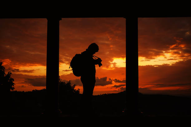 silhouette small of photographer taking photo on the mountain and the sunrise golden hour at morming background
