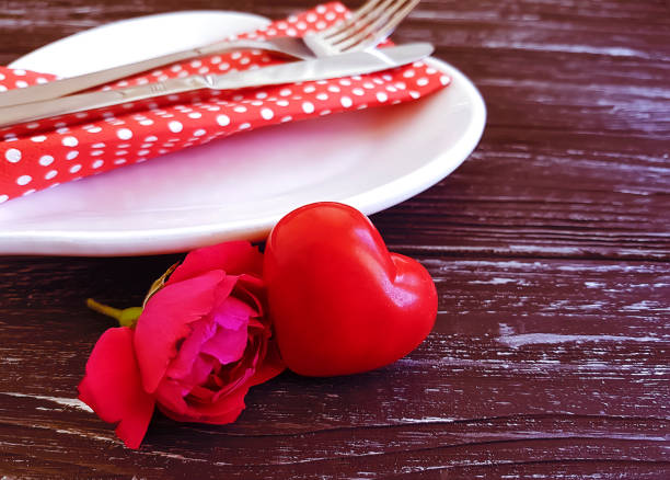 istock fork, knife, plate heart, flower rose on wooden background 1053113844