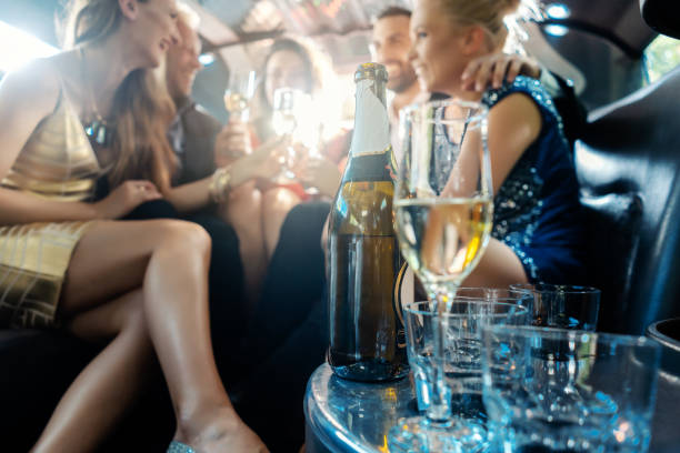 women and men celebrating with drinks in a limousine car - limousine imagens e fotografias de stock