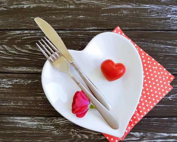 istock fork, knife, plate heart, flower rose on wooden background 1053118972