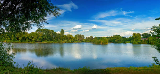 istock Tranquil landscape at a lake, with white clouds sky and the trees reflected in the clean blue water 1053119566