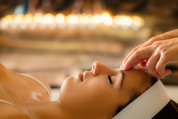 face shot of woman having ayurvedic massage at low candle light. - reiki alternative therapy massaging women imagens e fotografias de stock