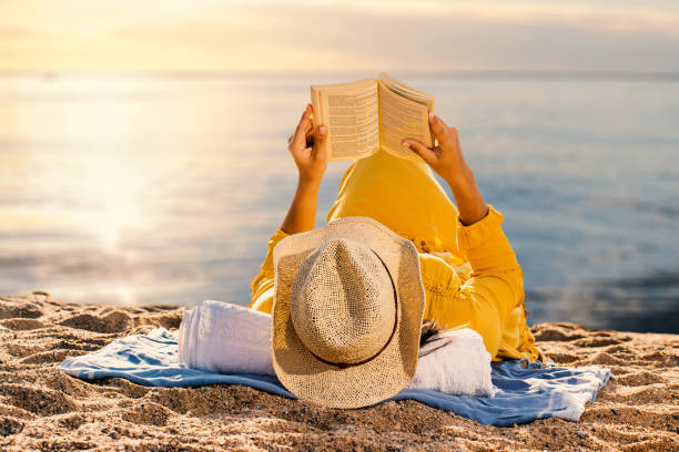 istock Woman reading a novel at sunset on beach. 1053134530