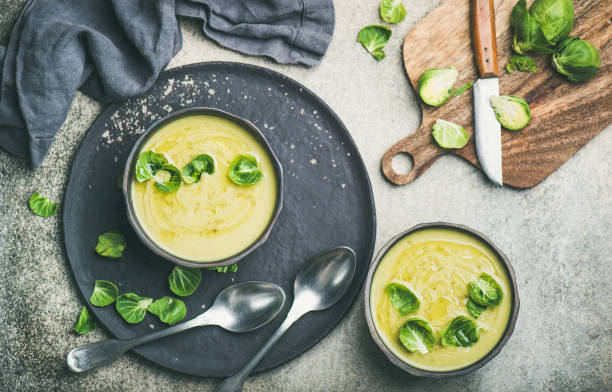 posa piatta di bruxelles stagionale germoglia zuppa di crema vegetale in ciotole - cream of broccoli foto e immagini stock