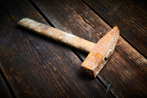 Close up of old used hammer on a rustic wooden background.