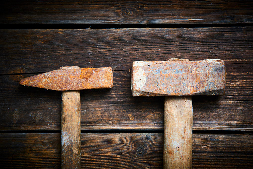 Close up of two old used hammer on a rustic wooden background.