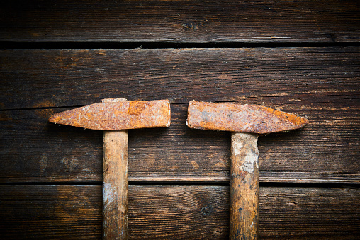 Close up of two old used hammer on a rustic wooden background.