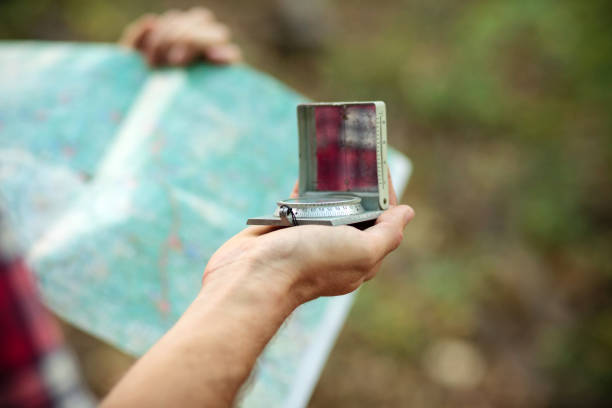 istock Close up of a man's hand holding and using an old-fashioned compass and map for navigation 1053152286
