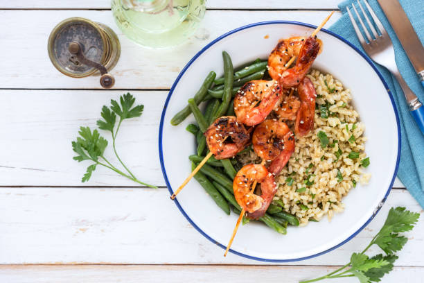 Brown rice with green beans and glazed shrimp skewers stock photo