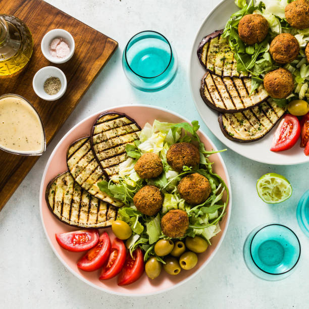 istock an appetizing dinner or lunch from a salad with tomatoes, grilled eggplants and legume falafel with sesame tahini dressing. Vegan healthy food for the whole family 1053171432
