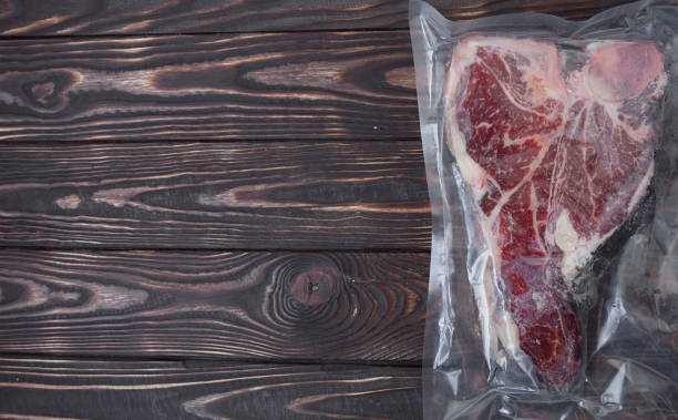 istock Vacuum packed meat on old wooden background. 1053173928