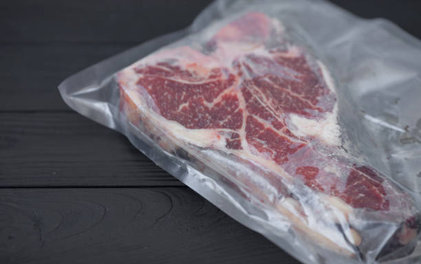 istock Vacuum packed meat on old wooden background. 1053174166