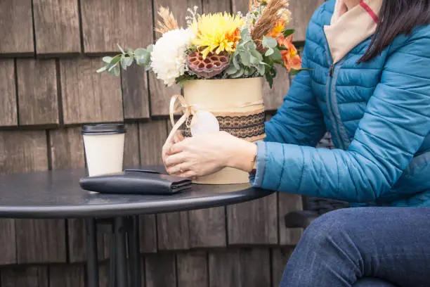 The girl sits in a cafe in the wicker chair in the fall and is waiting for a meeting.