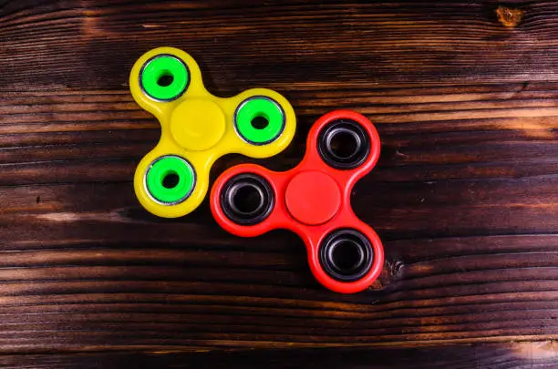 Photo of Two fidget spinners on wooden desk. Top view